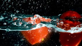 Red bell peppers on a black background submerge in water, rotate, float to the surface and form bubbles. Slow motion mode. Close-up. - Powered by Shutterstock - Get 15% off with code: PIKWIZARD15