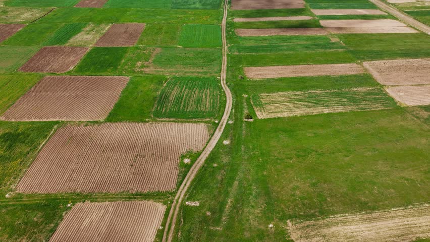 Aerial wide angle view of typical agricultural landscape with green fields in the foreground blue sky with clouds casting shadows on the land.	
