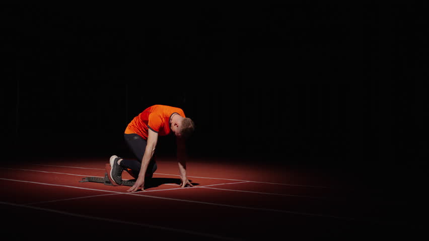 Sprinter Preparing To Start, Athletic Man Standing On Starting Blocks In Sprint Lane, Slow Motion