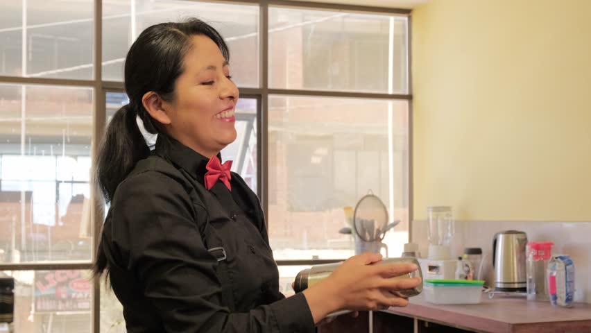 latina bartender woman in black clothes mixing a drink with alcohol at home - beverage concept