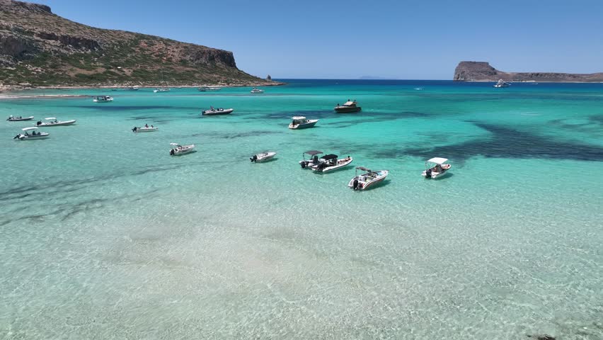 Motor boats anchored in the turquoise water of the Balos Beach Lagoon in Crete, Greece