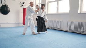Two men training aikido with one applying joint arm control Sankyo technique They are dressed in traditional martial arts kimono and Hakama. Active people and Japanese culture 4K footage. - Powered by Shutterstock - Get 15% off with code: PIKWIZARD15