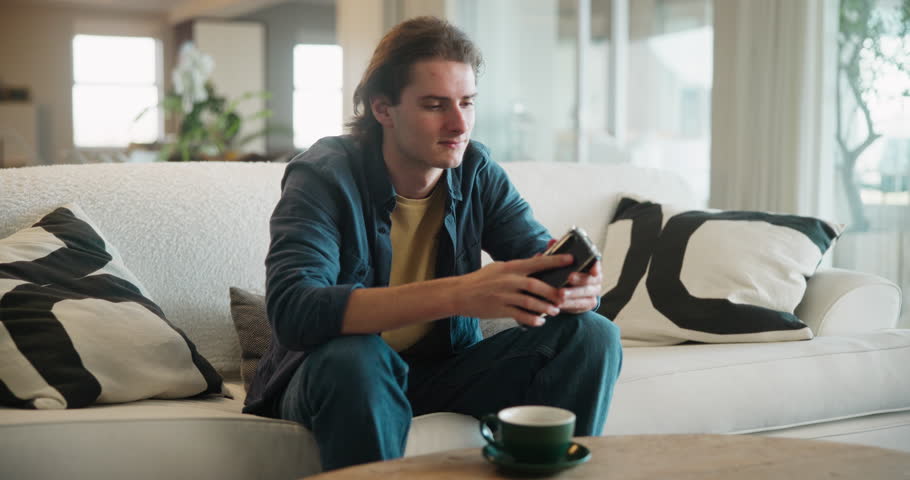 Phone, relax and man on sofa with social media, streaming or gaming service, subscription or sign up at home. Smartphone, app and gen z student in living room with elearning, research or registration