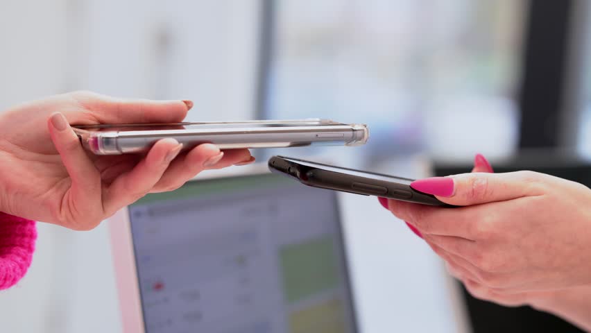 Two women use tapping cashless wifi qr code nfc scan app smart pos device reader sale in modern beauty clinic. NFC contactless technology.