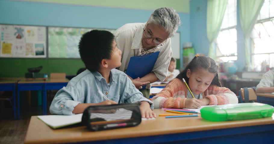 Education, teacher and kids in classroom for help, explain and learning in elementary school. Woman, students and diversity at desk for solution, assessment and knowledge while coloring together