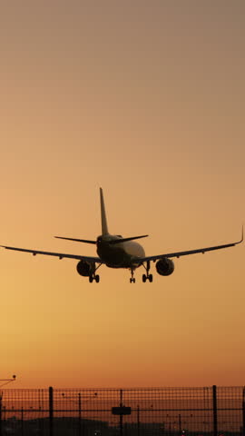 Vertical Screen: A stunning scene unveils as a plane smoothly touches down at dusk against a vibrant orange sunset backdrop, encapsulating the essence of aviation, travel, and the expansive skies