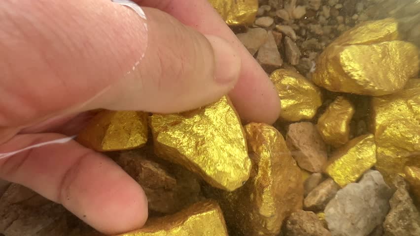 hand holding gold ingot with rising and falling prices on black background.