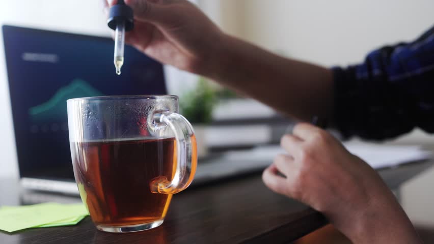 Cbd oil. Business woman taking cannabis drop in tea drink for anxiety and stress treatment. Alternative medicine