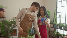 A man and woman, florists, collaborate in an indoor flower shop, surrounded by plants, discussing flower arrangements using a tablet. - Powered by Shutterstock - Get 15% off with code: PIKWIZARD15
