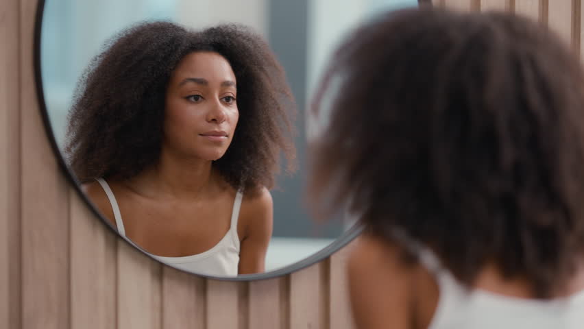 Beautiful pretty healthy African American woman girl female lady ethnic wipe clean face with towel washing facial beauty morning hygiene procedure routine skin care moisture cosmetic looking mirror