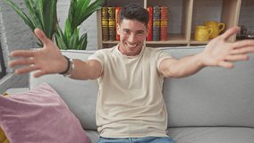 Joyful young hispanic man, sitting on a sofa at home, arms wide open for a warm hug. handsome male flashing a cheerful smile to the camera, radiating happiness and love - Powered by Shutterstock - Get 15% off with code: PIKWIZARD15