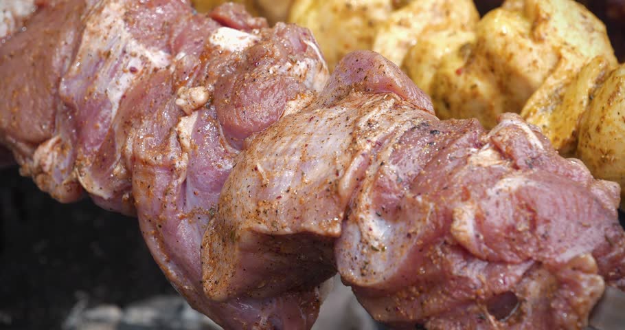 Shish kebab. Marinated meat with seasoning rotates on a spit. Shish kebabs broils in barbecue. Meat are cooked on hot coals in barbecue, rotates on a skewer for roasting