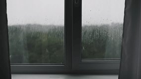 Relaxing footage of raindrops flowing down a windowpane, blurring the view of trees and the overcast sky. Perfect for creating a cozy and atmospheric mood. - Powered by Shutterstock - Get 15% off with code: PIKWIZARD15