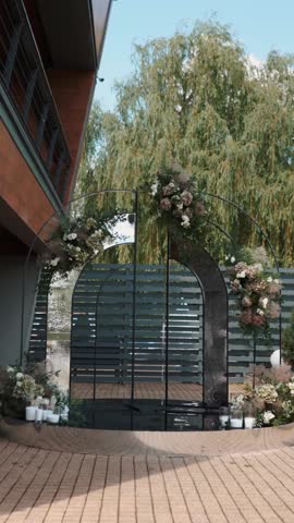 wedding arch of white rose flowers on the river bank before the wedding ceremony of the bride and groom, festive romantic decor