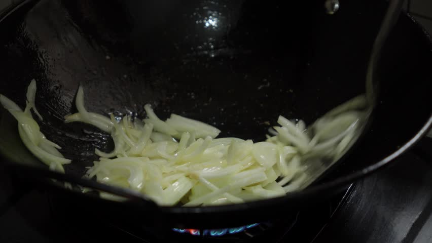 Sauteing onions in a Chinese metal wok over high heat