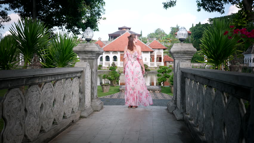 Female travel content creator in summer dress explores Bali Ujung Water Palace
