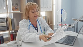 A middle-aged caucasian female doctor in a clinic office, holding and discussing a medical document with a patient, surrounded by office equipment and medical supplies. - Powered by Shutterstock - Get 15% off with code: PIKWIZARD15