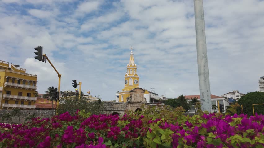 Iconic Torre del Reloj monument in Cartagena with vibrant flowers and clear sky, colombia