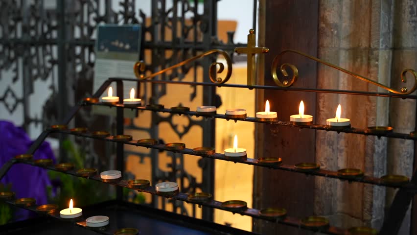 Several small lit wax candles flickering in St Davids Cathedral, Wales