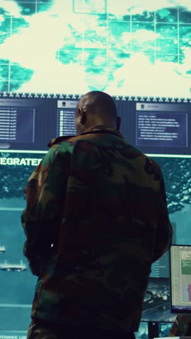 Vertical Video General of the army overseeing special reconnaissance mission in control center, undertake intelligence gathering operations with CCTV footage and a world map on a big screen. Camera B.