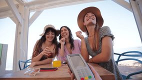 Happy young group of only women paying the bill with a contactless credit card in cocktail beach bar. Female smiling holding a creditcard and giving a payment transaction to the cashier on vacations - Powered by Shutterstock - Get 15% off with code: PIKWIZARD15