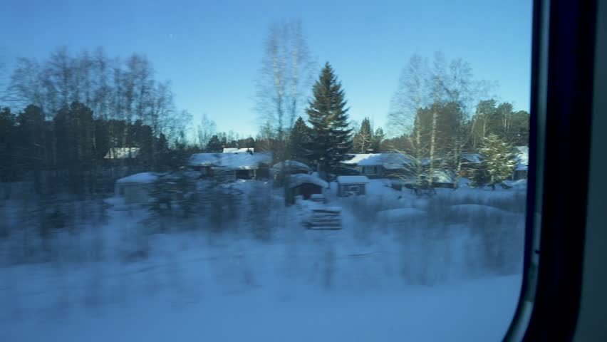 Traveling by train through a snowy forest, passing homes with snow-covered roofs