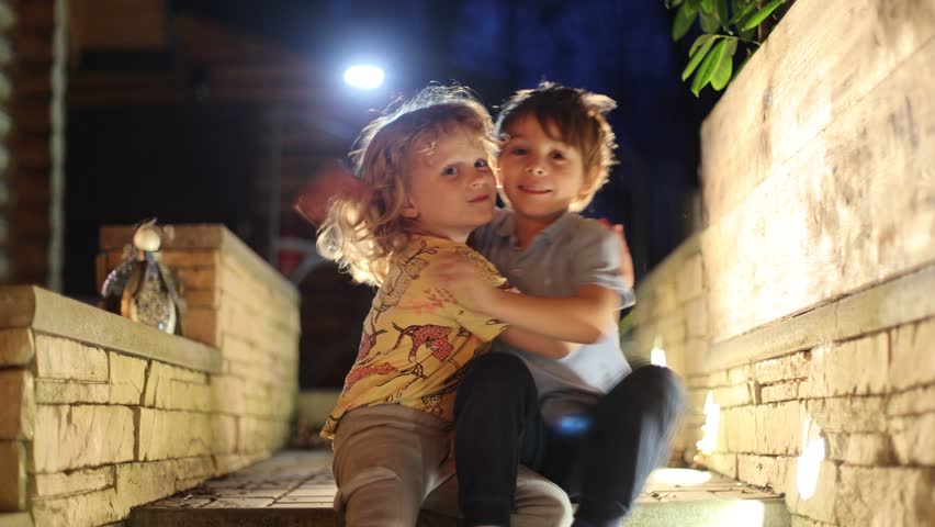 Happy children oudoors at night, having fun laughing and enjoying warm spring night	