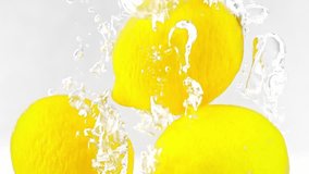 Three lemons are falling into water filmed in closeup slow motion on white background. Some fresh yellow citrus dropped into clear and transparent aqua. Nice ingredients to prepare homemade lemonade - Powered by Shutterstock - Get 15% off with code: PIKWIZARD15
