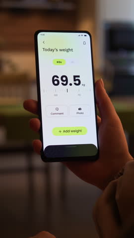 Tracking weight loss progress. Monitoring weight loss using fitness app for mobile phone. Fictional Interface, vertical video.
