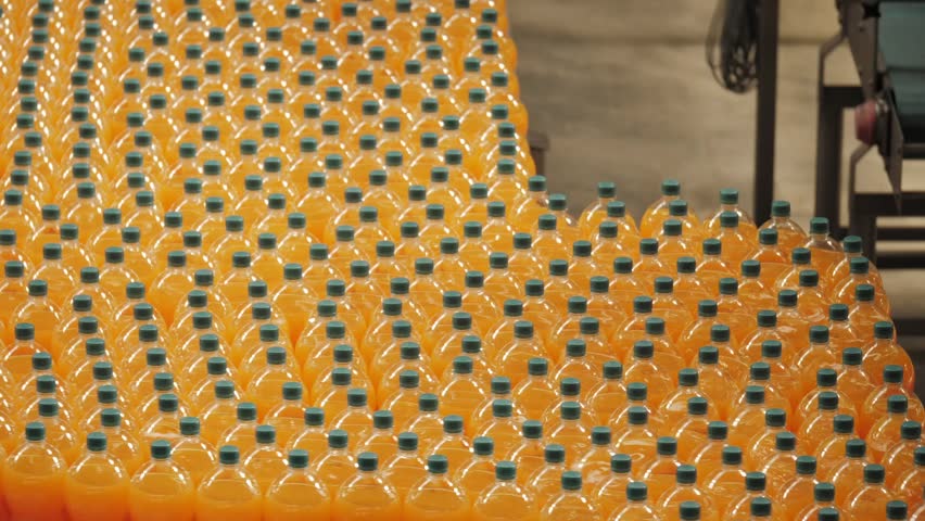 Many lines of juice plastic bottles flowing on a conveyor in a beverage factory