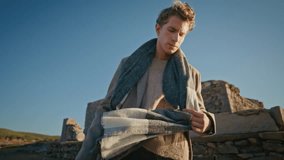 Thinking man touching scarf resting windy nature closeup. Calm serious guy looking down walking abandoned castle nature alone. Pensive model in autumn clothes strolling grassy hills. People lifestyle - Powered by Shutterstock - Get 15% off with code: PIKWIZARD15
