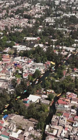 Sunlit drone perspective of Xochimilco trajineras in vertical orientation. CDMX