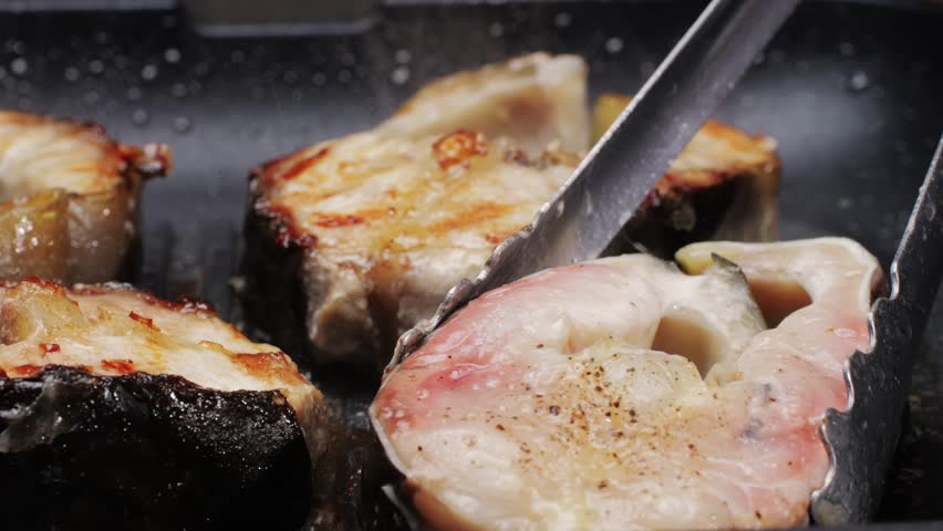 Cooking fillet sturgeon beluga white fat fish on grill or frying pan with oil close-up. Roast healthy food concept. Fry sturgeon, hake, cod fish steak pieces fillet. Healthy diet food with Omega 3. 