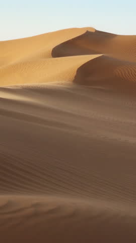 Sand blowing over sand dunes in wind, Sahara desert. Vertical video