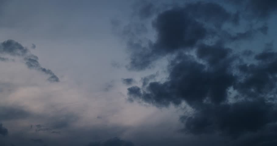 a darkening sky with clouds at sunset, a beautiful sky with slowly moving clouds in the sky at dusk