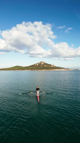 man rowing in the blue sea between mountains on a beautiful cloudy day