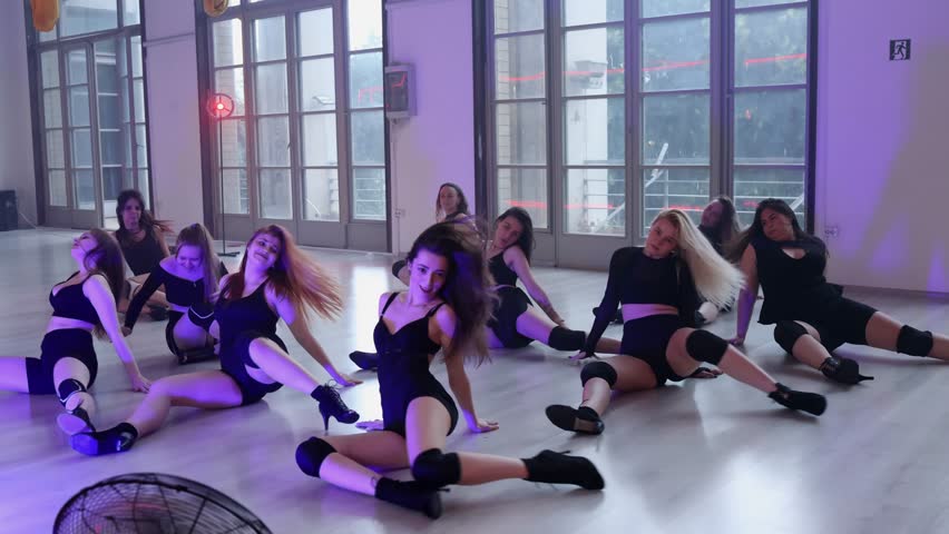A group of eleven girls are dancing a heels dance on the floor. Group dance lessons.