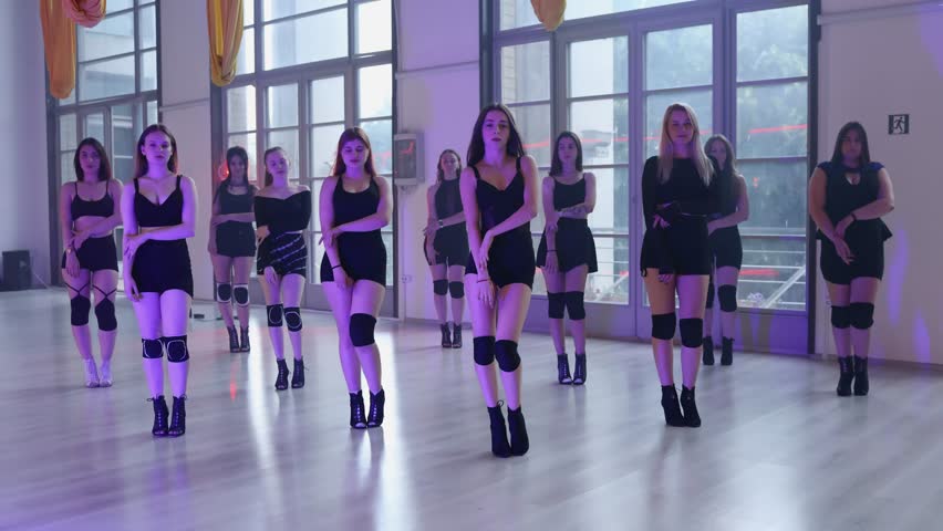 A group of sexy girls in high heels dance and flip their hair for the camera. Group heels dance in the evening purple light.