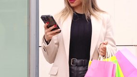  Unrecognizable young woman with shopping bags,using an app on smartphone