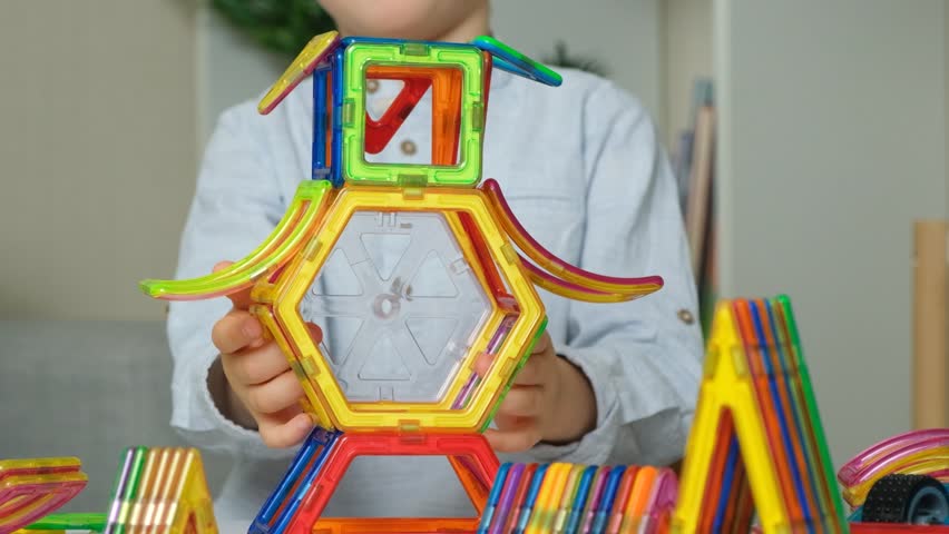 Child playing with magnetic constructor, hands close-up.