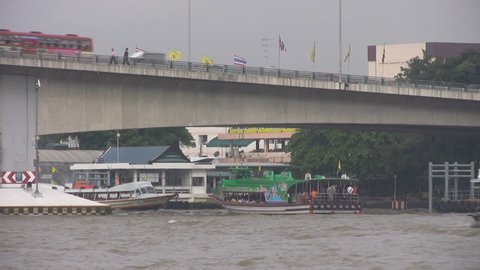 PINKLAO, BANGKOK, THAILAND - CIRCA 2012: Boats under Pinklao Bridge in Bangkok wait while traffic passes overhead.