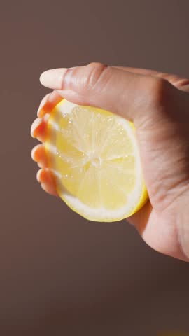 Female squeezing juice out of half a lemon in slow motion.