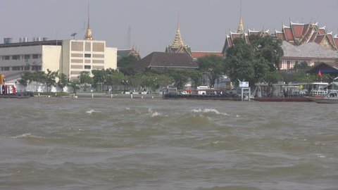 Boats on a busy stretch of the Chaopraya river in Bangkok with the Grand Palace behind.