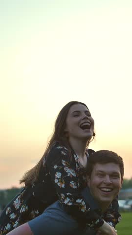 Happy couple playing in the summer field. Smiling, laughing and happiness. Supr slow motion shot. Sunset or sunrise natural lighting. Portrait handy shot. Lumix gh5. Vertical shot.