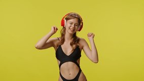 Young woman in swimsuit smiling dancing listening music in headphones. Travel, summertime vacation, beach leisure time concept. - Powered by Shutterstock - Get 15% off with code: PIKWIZARD15