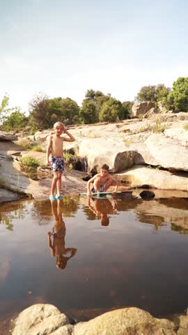 Two Caucasian children playing calmly in the river in summer