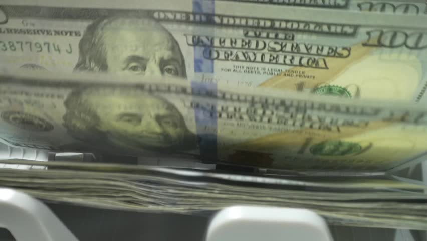 Close up of currency counting machine counting dollar bills. Banknote counter. Money counter with dollar bills. Money counter machine is counting American hundred dollars banknotes.
