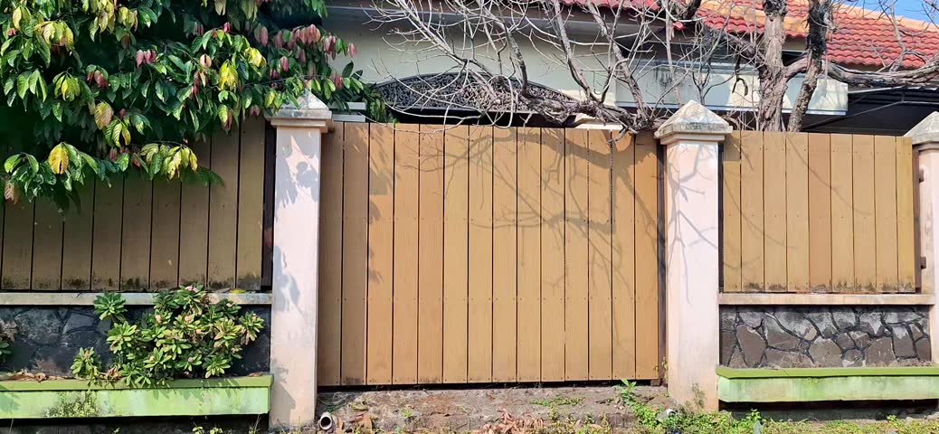 the appearance of a unique house covered by a wooden fence with trees around it