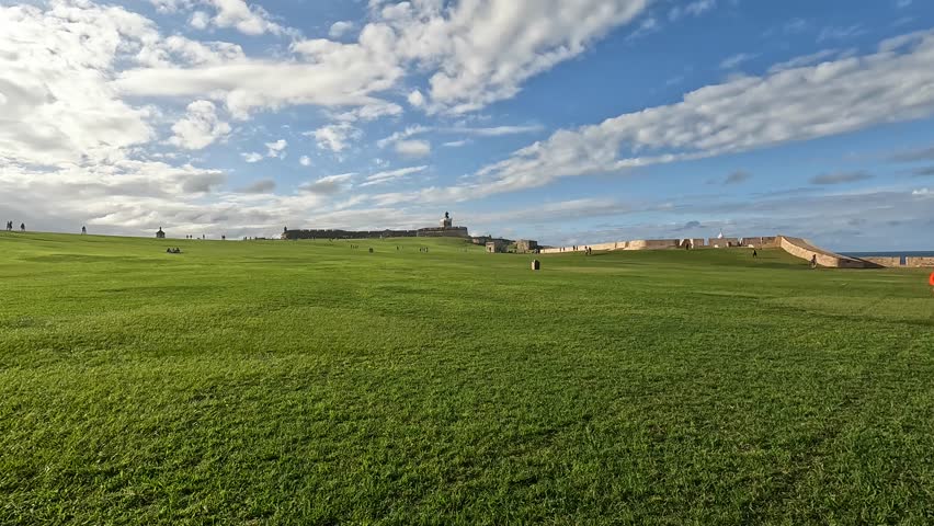 walking on the green lawn in front of castillo san felipe del morro (spanish colonial fort castle on hill old san juan puerto rico) beautiful national park travel tourism destination grass caribbean