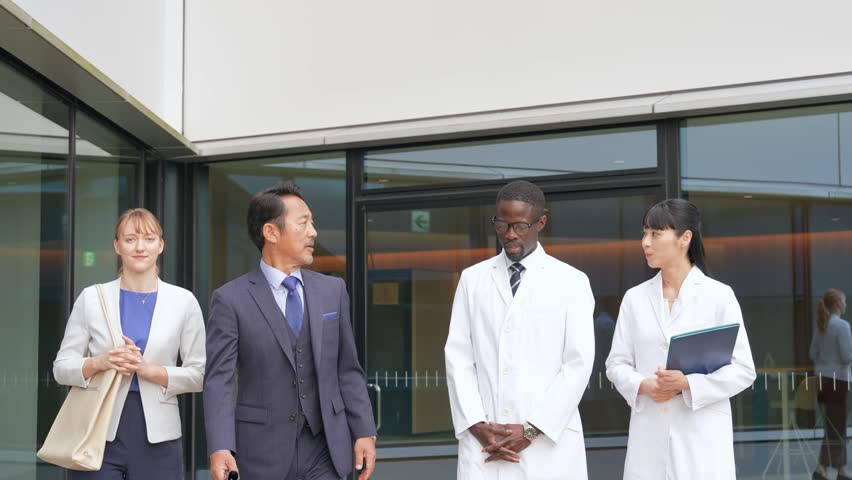 A group of multinational business people and engineers in white coats walking and talking